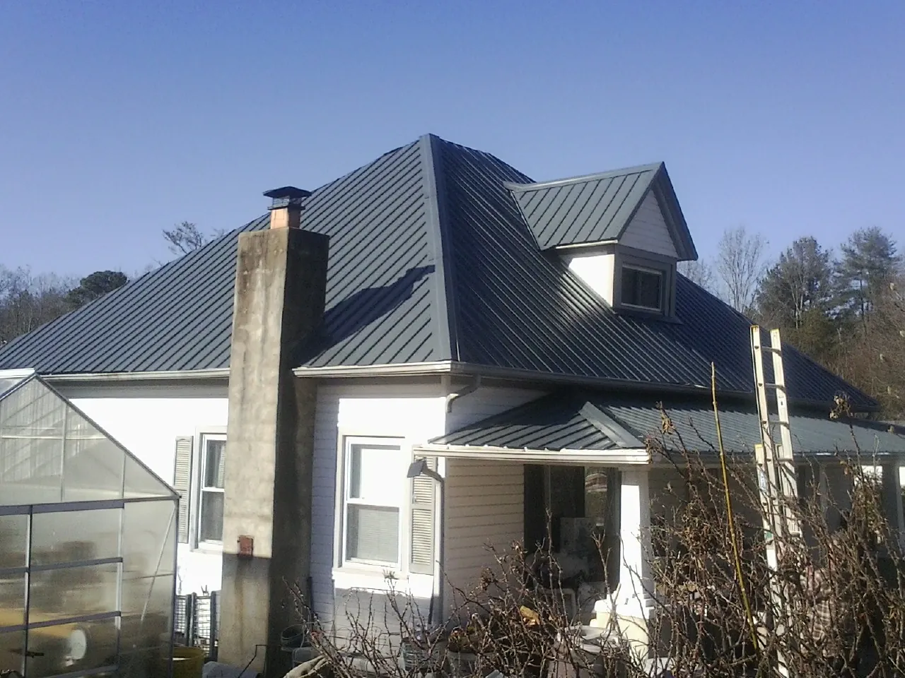 Dark blue standing seam metal roof on a white farmhouse with dormer — Slate & Tile Roof Repair by Roofing Brothers in Cheswold