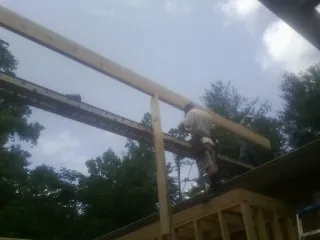 Carpenter setting a ridge beam over a new addition frame — Ice Dam Removal by Roofing Brothers in Cheswold