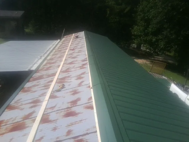 Old rusted panels beside newly installed green metal roofing — Wind Damage Roof Repair by Roofing Brothers in Cheswold
