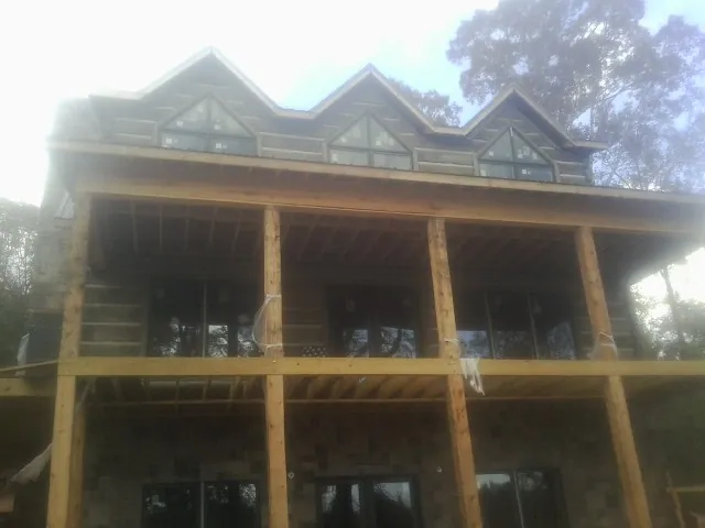 Dormers and porch framing on a large log home under construction — Roof Coating work by our crew in Cheswold
