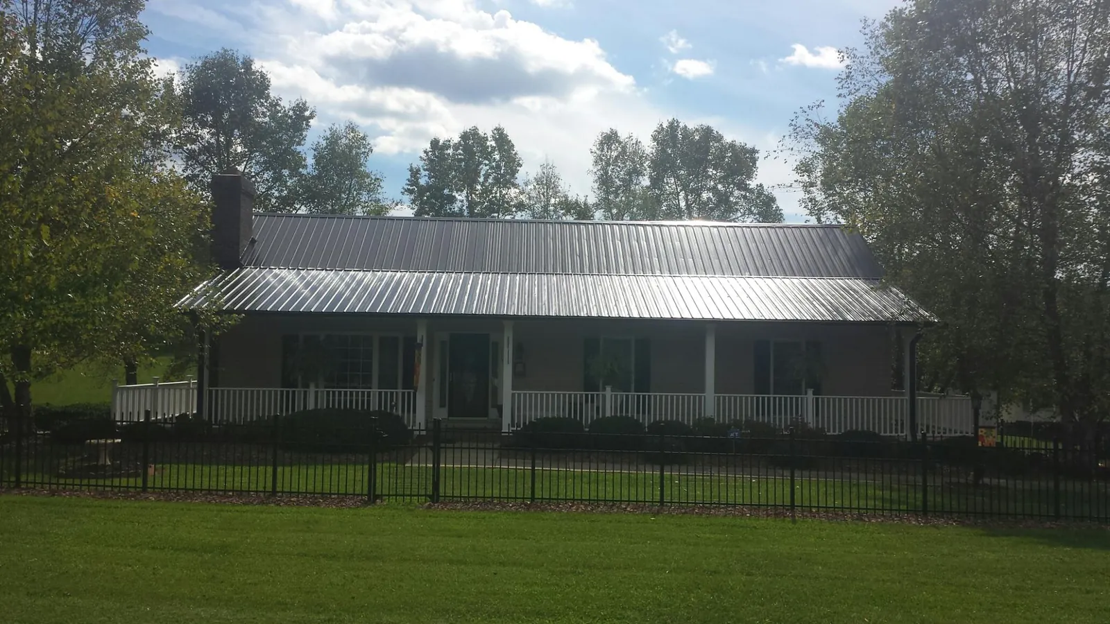 Gray metal roof on a brick ranch with a full width front porch — Gutter Guard Installation work by our crew in Cheswold