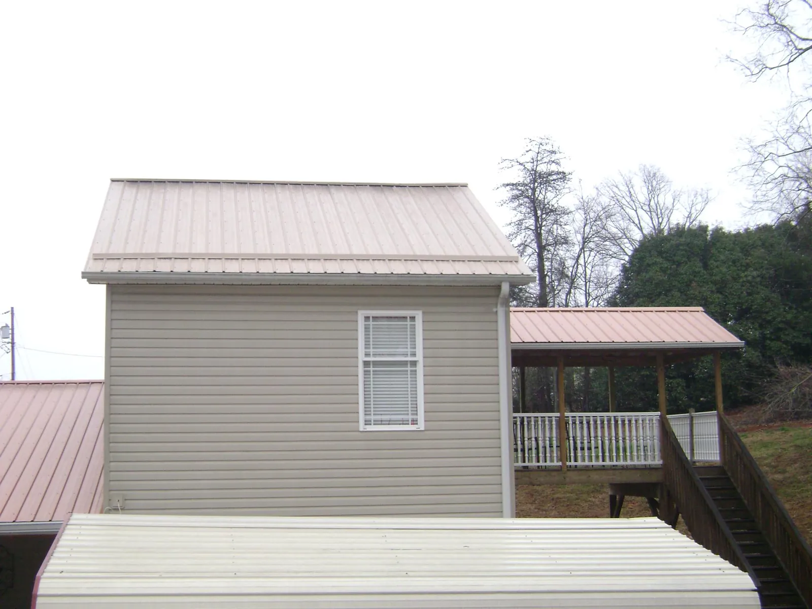 Tan metal roofs on a two story addition and attached porch, from a Roof Replacement job in Cheswold