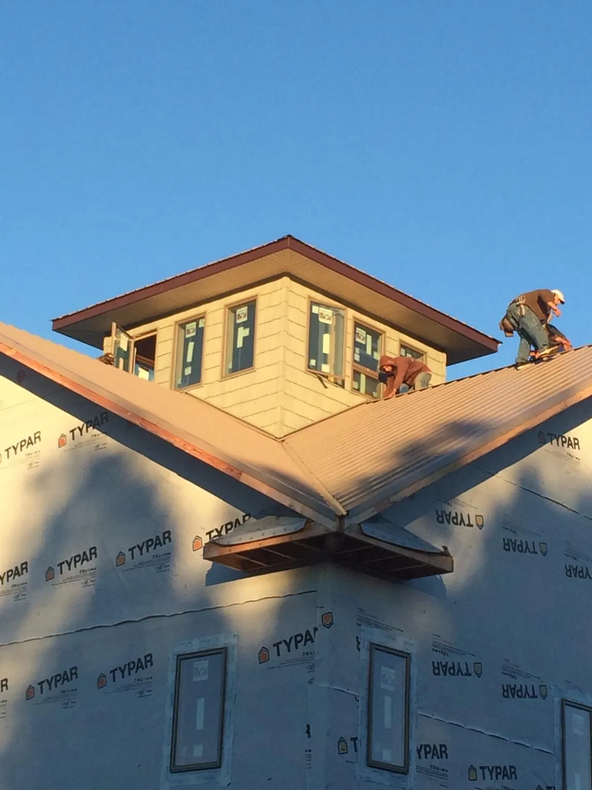 Roofers working around a rooftop cupola on a new metal roof at sunset — Roof Waterproofing in Cheswold by Roofing Brothers